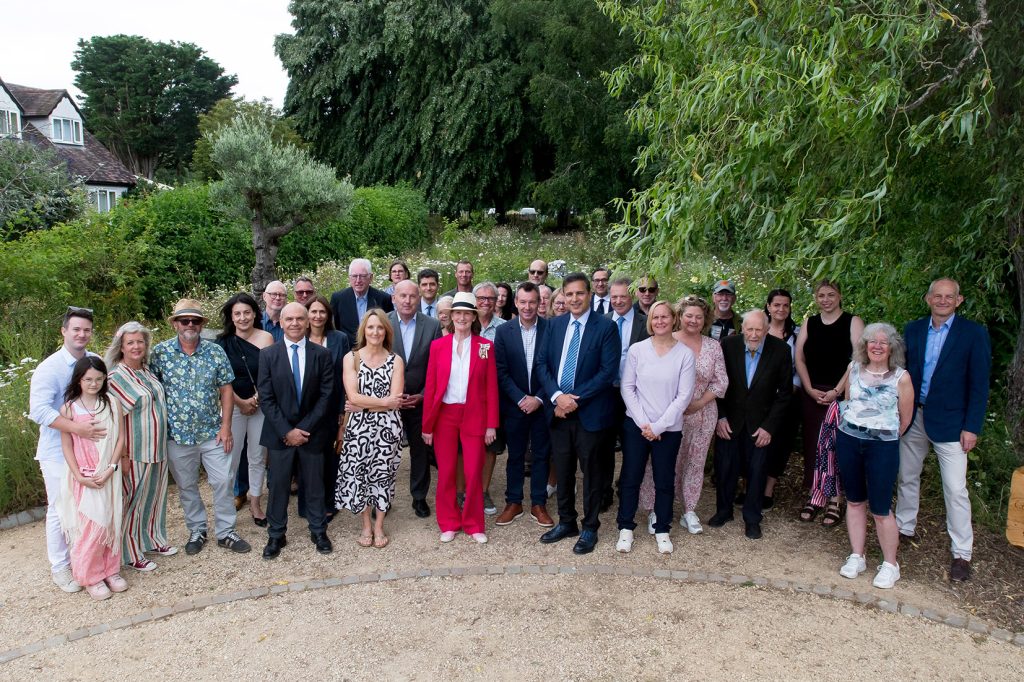 A large group of people pose for a photograph in a community garden.