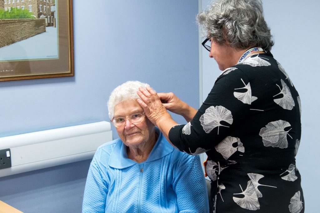 An elderly lady having a hearing aid fitted.
