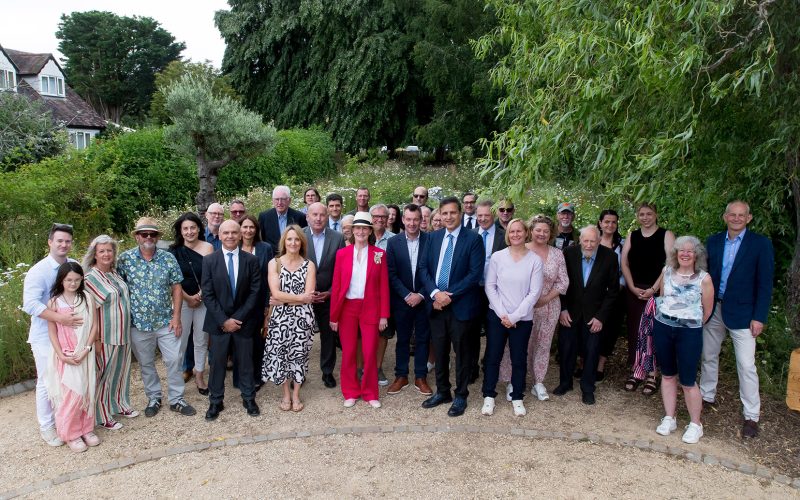 A large group of people pose for a photograph in a community garden.
